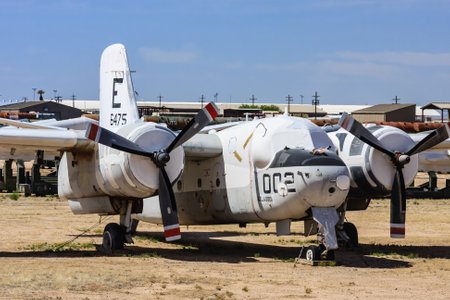 A large propeller plane is sitting on the ground in a desert. The plane is old and has a red and...