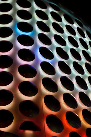 A colorful pattern of circles is lit up in the dark. The circles are of different sizes and colors,...