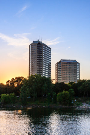A beautiful sunset over a city skyline with two tall buildings in the background. The water is calm and reflects the sky and the buildingsの写真素材