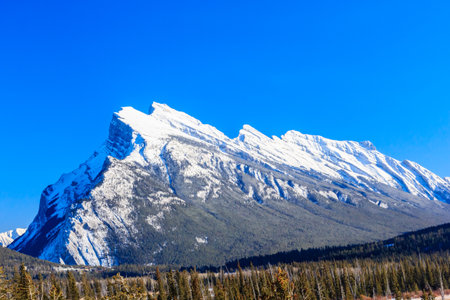 A mountain with snow on it and a blue sky in the background. The mountain is very tall and the sky is clearの写真素材