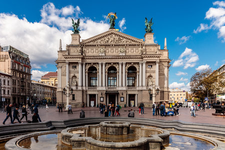 A large building with a fountain in front of it. The fountain is surrounded by people. The building is a theaterの写真素材