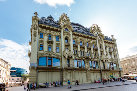 A large building with a lot of windows and a clock on the side. People are walking around the areaの写真素材