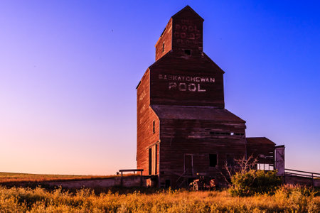 A large, old grain silo with a sign on it that says "Pool House School". The silo is surrounded by a field and the sky is a beautiful blueの写真素材