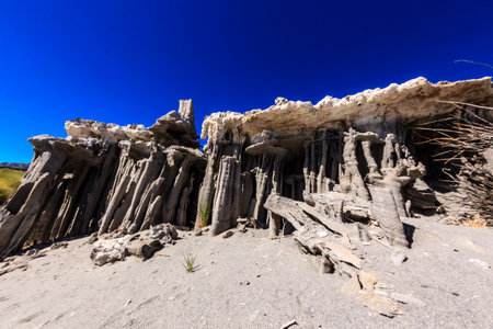 A rocky cliff with a blue sky in the background. The cliff is made of rocks and has a lot of holes