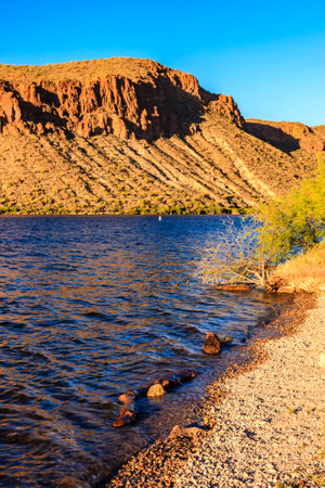 A beautiful mountain range with a lake in the foreground. The water is calm and the sky is clearの写真素材