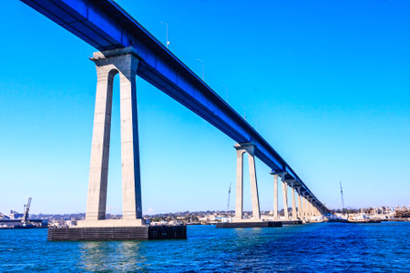 A large bridge spans a body of water, with a blue sky above. The bridge is a modern structure, and the water below is calm and clear. Concept of tranquility and serenityの写真素材