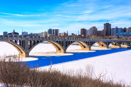 A bridge spans a river with a blue tint. The city below is bustling with activity. The bridge is a symbol of connection and progressの写真素材