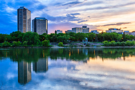 A city skyline with a river running through it. The sky is a mix of blue and orange, creating a warm and peaceful atmosphereの写真素材