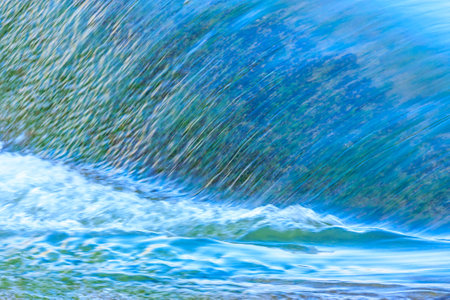 A large wave crashing into the shore. The water is a deep blue color, and the waves are crashing...