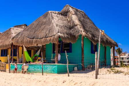 A small house with a blue roof and a green awning. The house is surrounded by a fence and a beachの写真素材