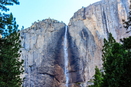 A waterfall is flowing down a cliff face. The water is clear and the rocks are brown. The scene is peaceful and sereneの写真素材