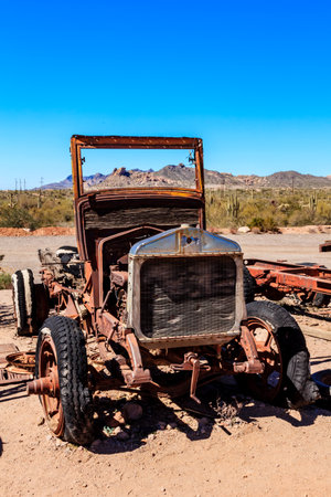 An old truck is sitting in the desert. The truck is rusted and has a broken windshield. The desert landscape is barren and desolateの写真素材