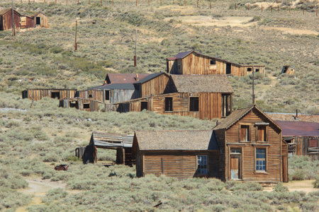 A group of old wooden houses are in a desert. The desert is dry and barrenの写真素材