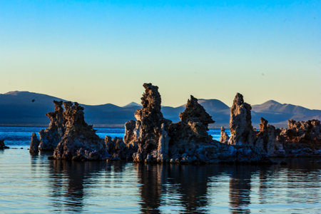 A rocky shoreline with a body of water in the background. The water is calm and the sky is blueの写真素材