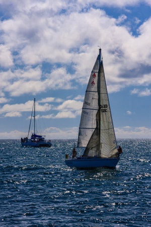 A sailboat is sailing in the ocean with a cloudy sky in the background. The sailboat is the only one...