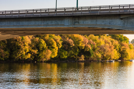 A bridge over a river with trees in the background. The trees are in autumn and the water is calmの写真素材