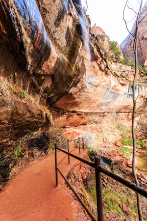 A stone wall with a railing and a path leading up to it. The railing is made of metal and the path is made of stone. The wall is very tall and the railing is very narrowの写真素材