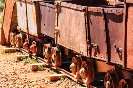 A train with old rusty wheels and a rusted caboose. The train is parked on a dirt trackの写真素材