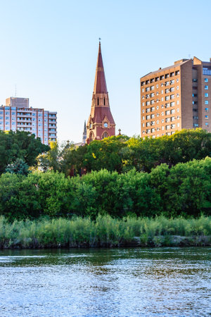 A church steeple is visible in the distance behind a green forest. The sky is clear and blue, and the water is calm. Concept of peace and tranquilityの写真素材