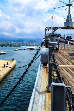 A ship is docked at a pier with a chain hanging from the side of the ship. The water is calm and the sky is cloudyの写真素材