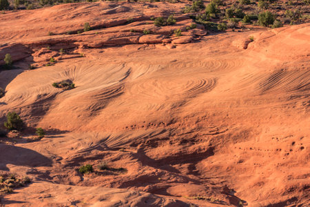 A desert landscape with a lot of rocks and dirt. The sun is setting and the sky is orangeの写真素材