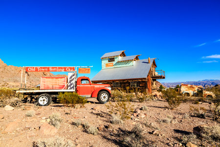 A red truck is parked in front of an old building. The truck is a vintage model and is parked in front of a building that looks like a barn. The building is old and has a rustic appearanceの写真素材