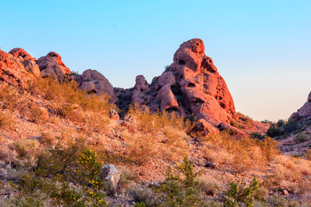 A rocky hillside with a large rock in the middle. The sun is setting and the sky is a beautiful blue colorの写真素材