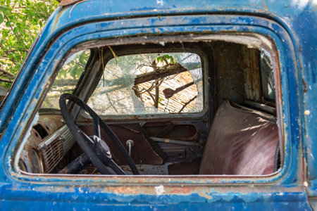 A blue truck with a cracked windshield and a leather seat. The seat is torn and the truck is oldの写真素材