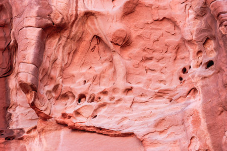 A rock wall with a lot of holes. The wall is red.の写真素材