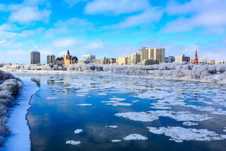 A city with a river running through it and a large building in the background. The water is frozen and the sky is blueの写真素材