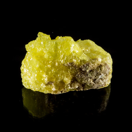 A yellow Sulphur Mineral rock on a black background. The rock is shiny and has a unique texture. It is a piece of quartz or some other type of mineralの写真素材