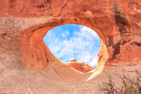 A large hole in a rock with a blue sky above it. The hole is large enough to fit a personの写真素材