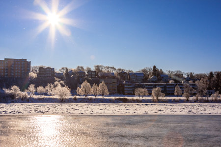 A snowy landscape with a bright sun shining on it. The sun is reflected on the water, creating a beautiful and serene sceneの写真素材