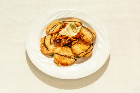 A plate of food with a white plate and a white table. The food is a mix of vegetables and meatの写真素材