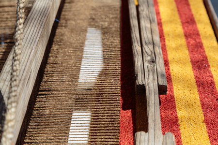 A wooden frame with a red and yellow striped rug underneath it. The frame is made of wood and has a rope tied to itの写真素材