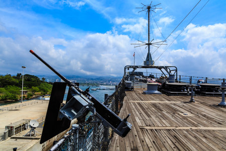 A small gun is on a boat in the ocean. The sky is blue and there are clouds in the backgroundの写真素材