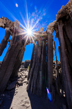 A large rock formation with a sun shining through it. The sun's rays create a beautiful and serene atmosphere, making the scene feel peaceful and calmingの写真素材