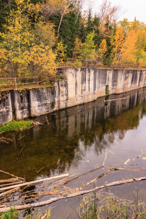 A river with a wall on the side. The water is calm and the trees are in the backgroundの写真素材
