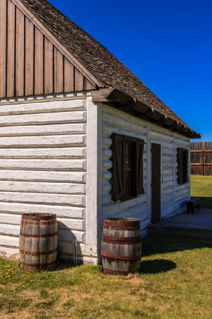 A white log cabin with a blue sky in the background. The cabin has a rustic feel to itの写真素材