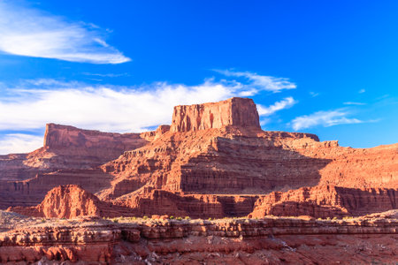 A mountain range with a cloudy sky in the background. The sky is blue and the mountains are red