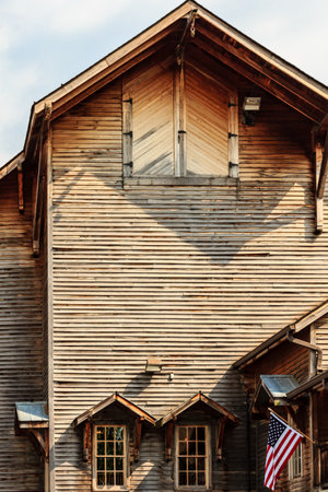 A large wooden building with a large American flag hanging from the roof. The building has a lot of wood and he is oldの写真素材
