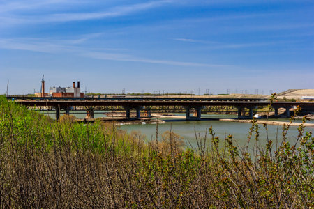A bridge spans a river with a green forest in the background. The bridge is surrounded by tall trees and the water is calmの写真素材