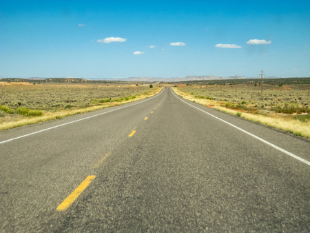 A long, empty road with no cars or people. The sky is blue and there are no cloudsの写真素材