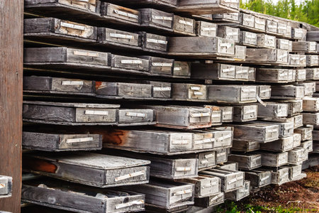 A stack of wooden crates are piled high. The crates are old and worn, and the wood is weathered. The...
