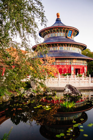 A large blue and red building with a blue roof. The building is surrounded by a pond with liliesの写真素材