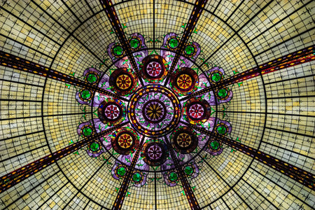 A stained glass window with a circular design. The window is filled with many different colored pieces of glassの写真素材