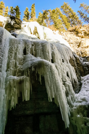 A large ice formation with icicles hanging from it. The ice is white and the sky is blueの写真素材