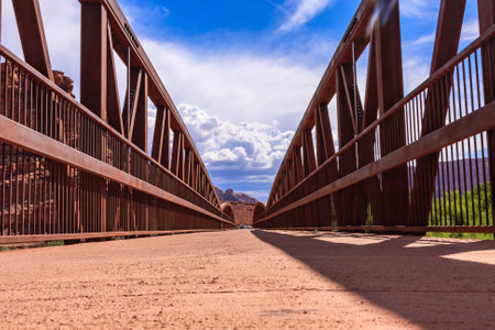 A bridge with a view of the mountains in the background. The bridge is made of metal and has a rustic appearanceの写真素材