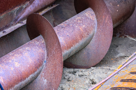 A rusty metal pipe with a spiral shape. The pipe is old and worn, with a rusted appearance