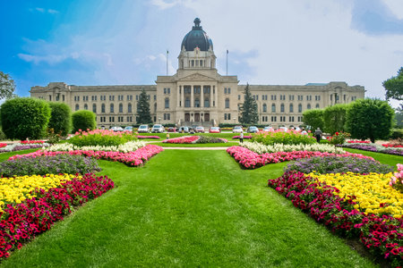 A large building with a dome on top and a large courtyard with flowers. The flowers are in a pattern of yellow, pink, and purpleの写真素材